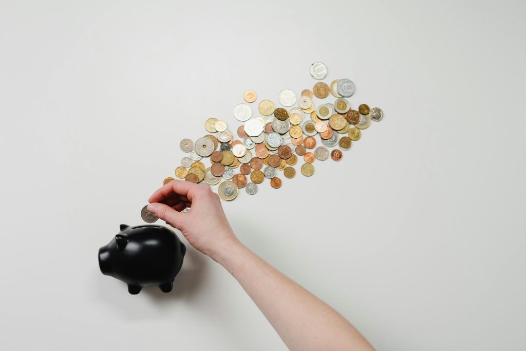 Hand saving money with coins and piggy bank, symbolizing real estate investment savings