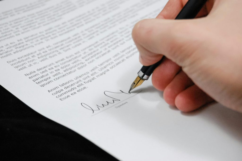 Close-up of hand signing real estate contract paperwork in Toronto