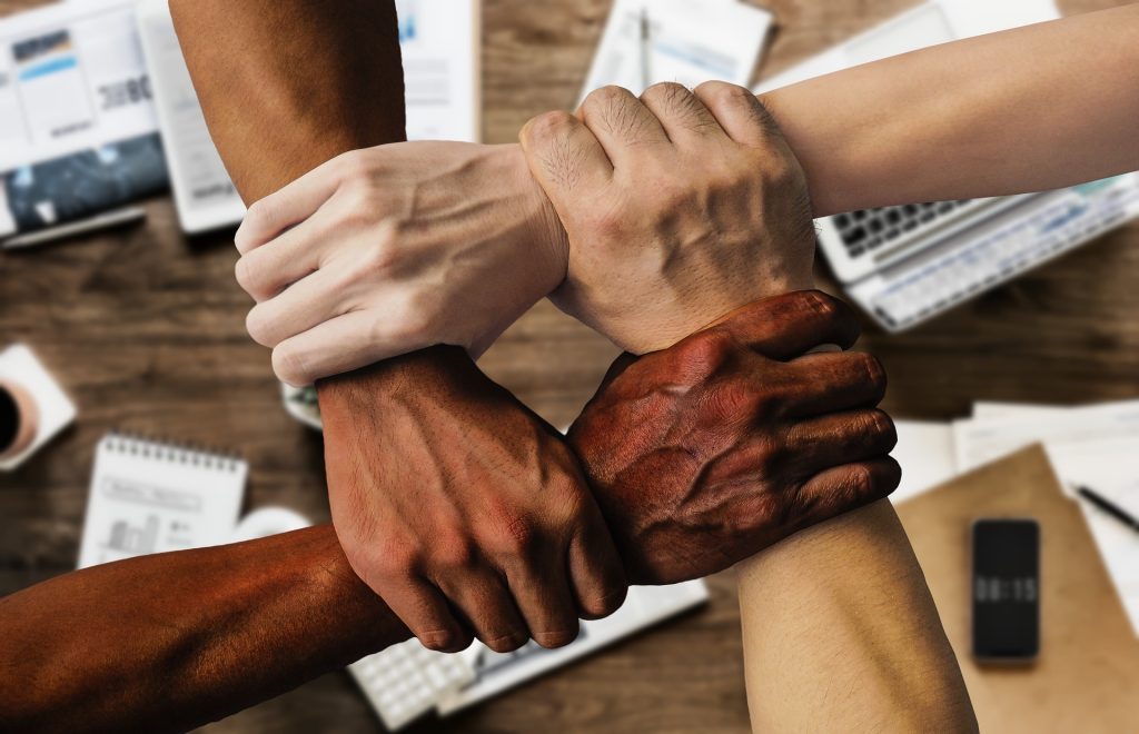 Team members joining hands to symbolize communication support and collaboration in real estate
